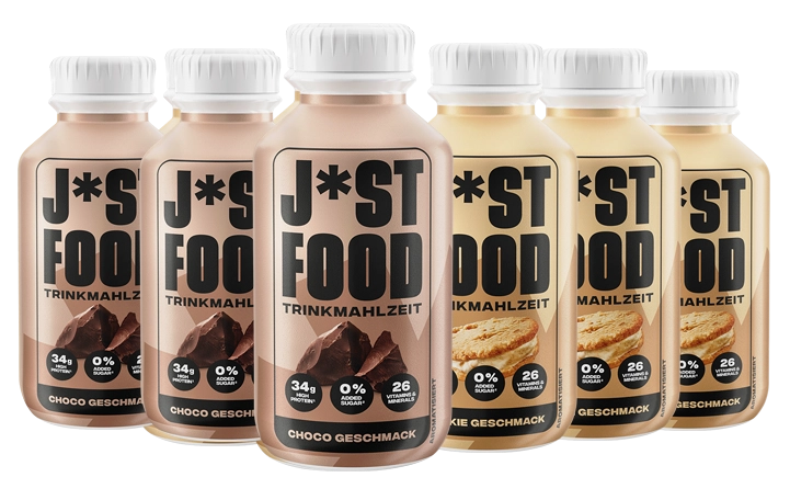Sechs Flaschen mit der Aufschrift "J*ST FOOD" stehen nebeneinander, wobei vier Schoko- und zwei Cookie-Geschmack zeigen; Text auf den Flaschen jeweils "TRINKMAHLZEIT" und "GESCHMACK".